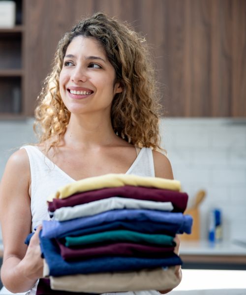 Happy woman holding pile of folded laundry