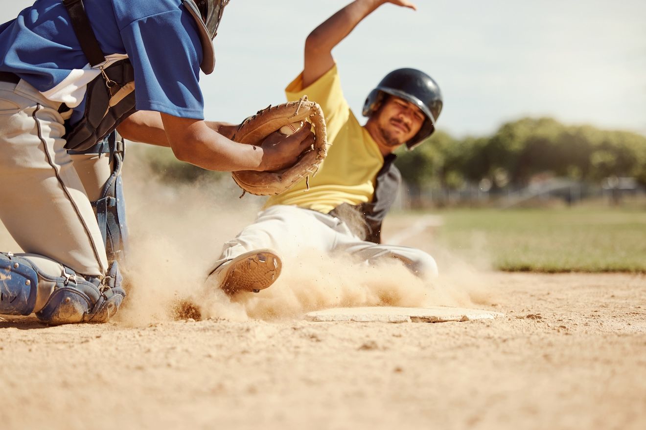 Baseball playing sliding in the dirt, staining his uniform.