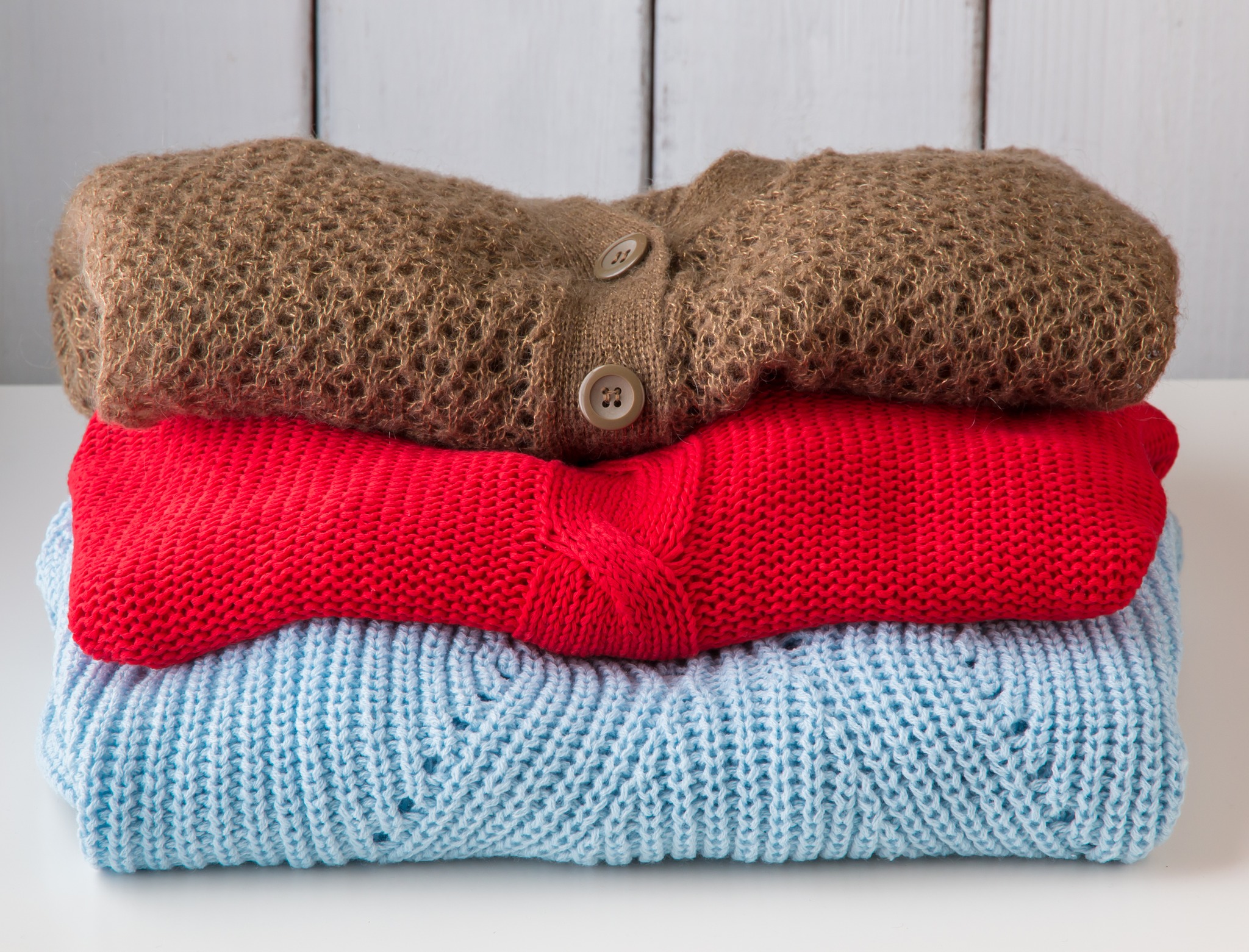 Stack of clean knitted sweaters and cardigans.